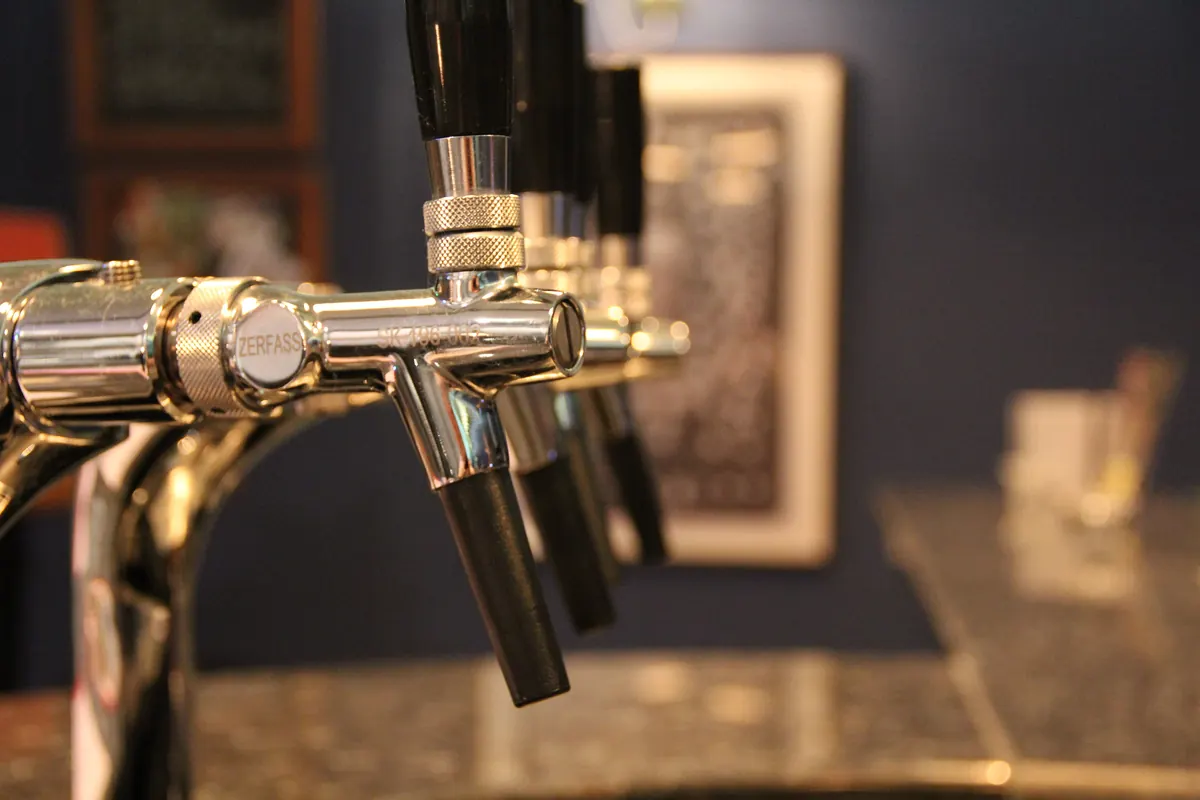 A row of chrome beer taps behind a bar