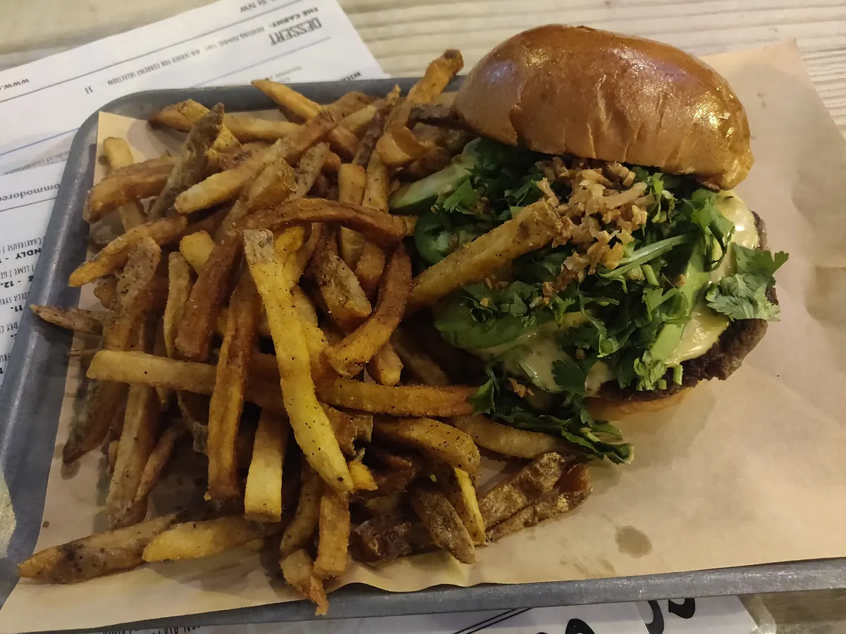 A cheeseburger and a pile of fries in a paper-lined tray
